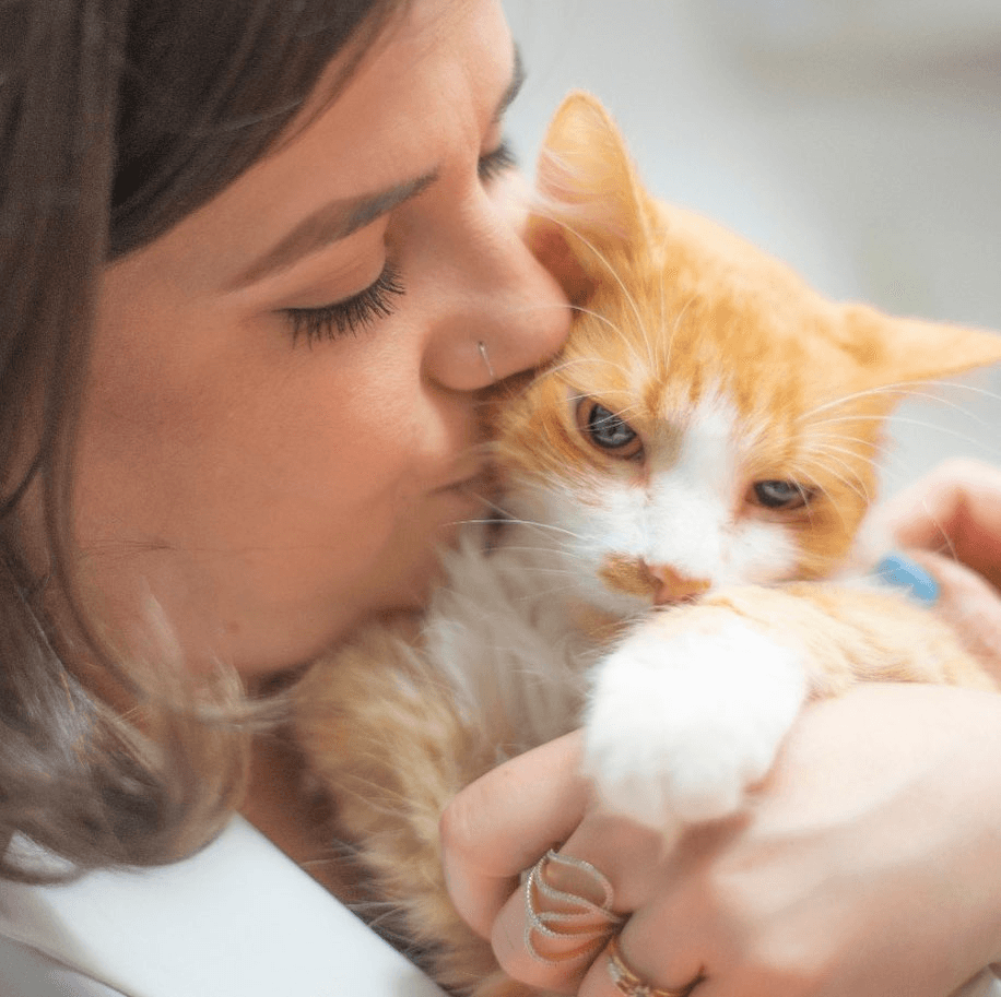 Nathália Herrera com o rosto encostado em um gato laranja no colo